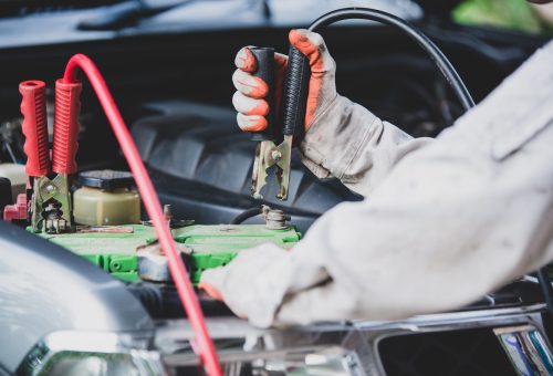 Car repairman wearing a white uniform standing and holding a wrench that is an essential tool for a mechanic